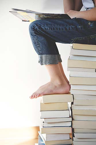 Child sits on top of a stack of books